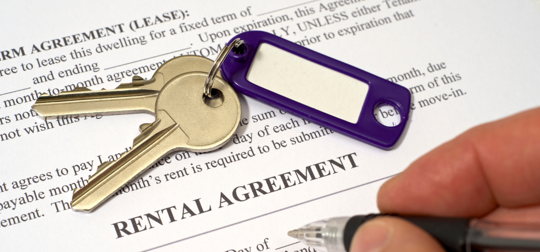two keys on a keychain on top of a rental agreement