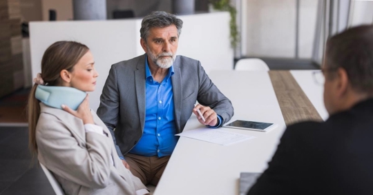 Client with neck brace meeting lawyer about personal injury lawsuit